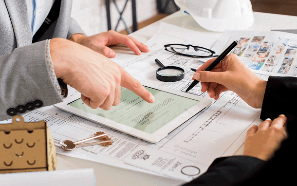Professional home inspection consultation with inspectors reviewing documents on tablet.