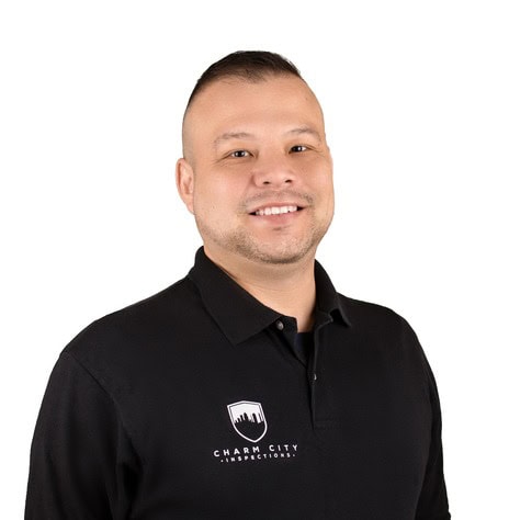 Home inspector smiling in uniform with Charm City Inspections logo.